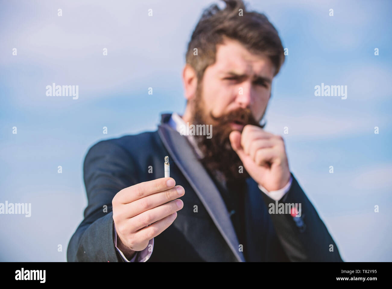 Bearded hipster smoking cigarette sky background. Guy cigarette enjoy  nicotine influence. Man with beard mustache hold cigarette. Cigarettes help  us with everything from boredom to anger management Stock Photo