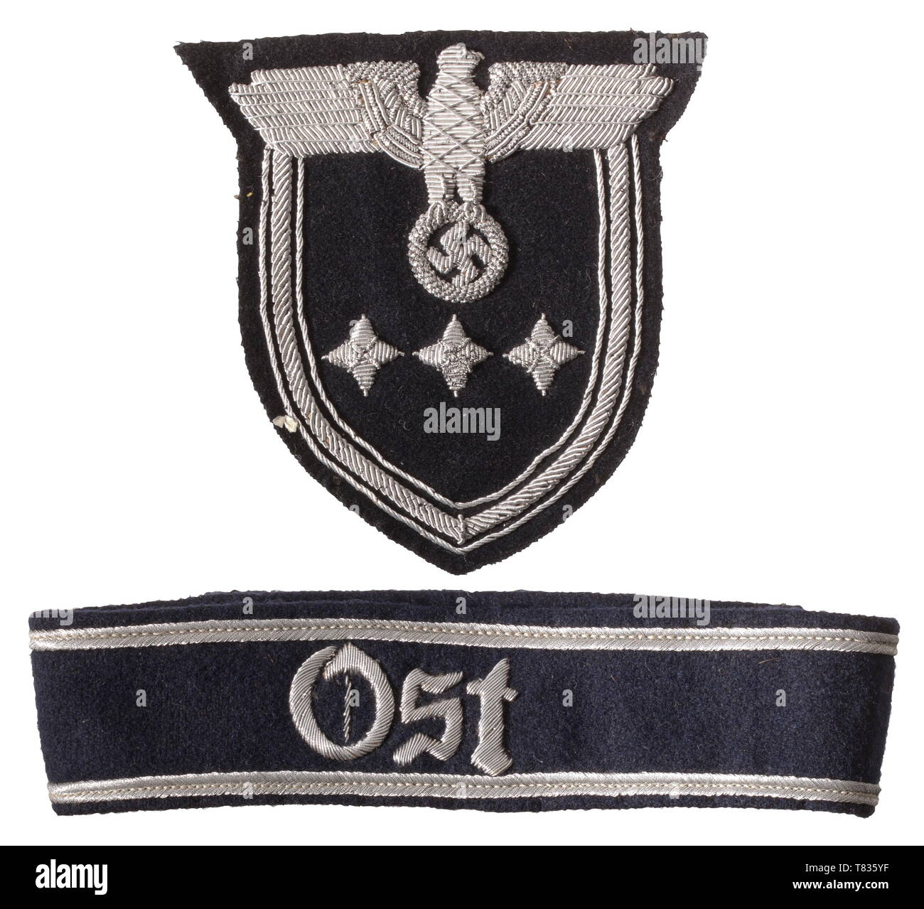 A cuff title 'Ost' for the General Gouvernement in Poland Included is a sleeve badge for members of the Diplomatic Corps (pay grade A2). The cuff title with hand-embroidered cyphers 'OST'. Dark blue base cloth with two silver weave borders, the reverse with linen reinforcement. Dimensions ca. 45 x 3.8 cm, with remnants of threads due to stitching. The sleeve badge made as before, with a rightward-looking hand-embroidered national eagle, the reverse with beige coloured paper covering. Dimensions ca. 10 x 10 cm. Cf. 'In the Service of the Reich', J, Additional-Rights-Clearance-Info-Not-Available Stock Photo