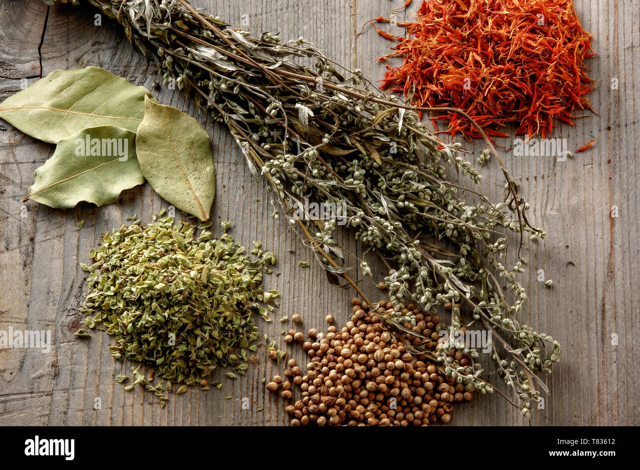 Mugwort, bay leaves, oregano, coriander and safflower on rustic wooden background Stock Photo
