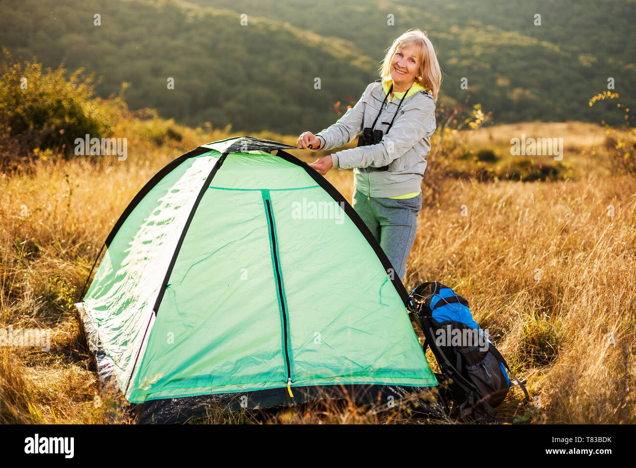 Senior woman is camping in mountain. Active retirement. Stock Photo