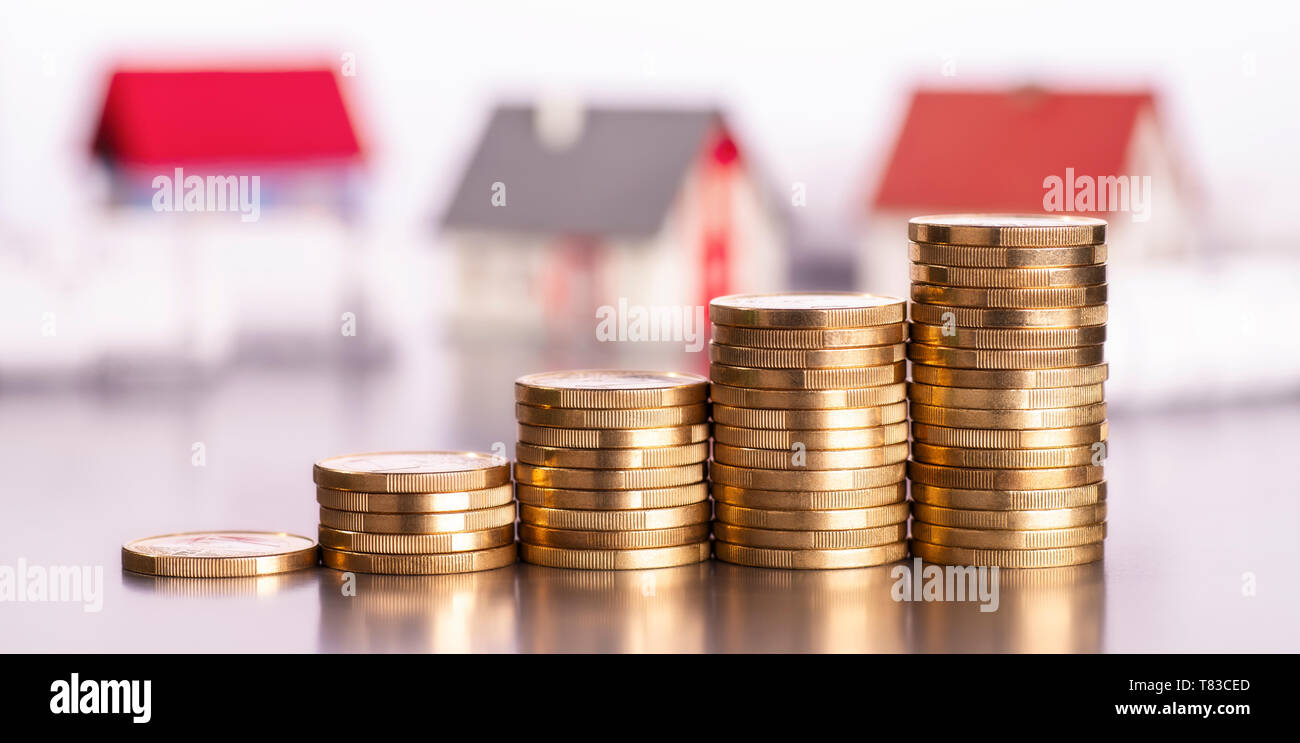 Rising stacks of coins with houses in the background Stock Photo