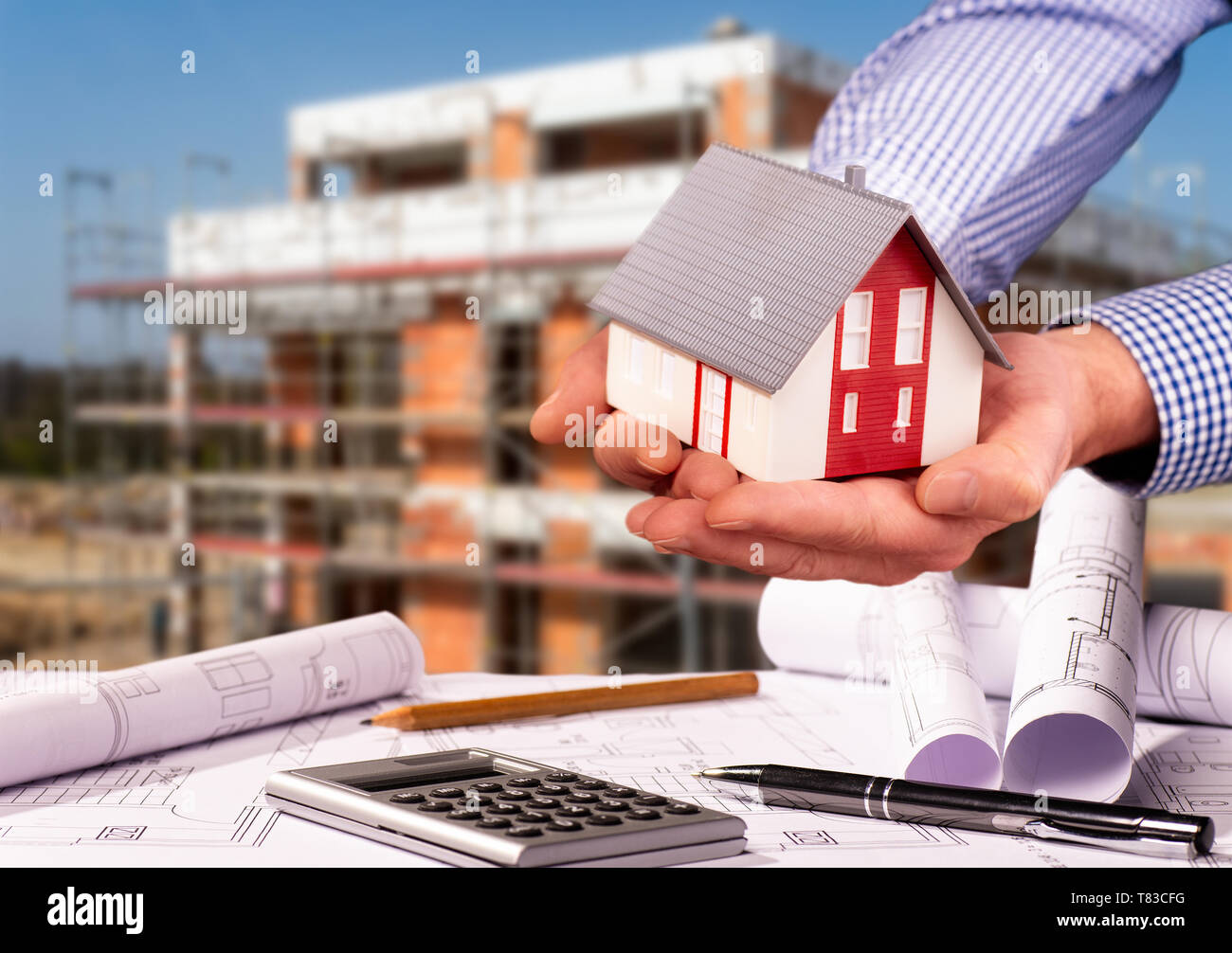 Construction plans with calculator, architectural model and a shell in the background Stock Photo