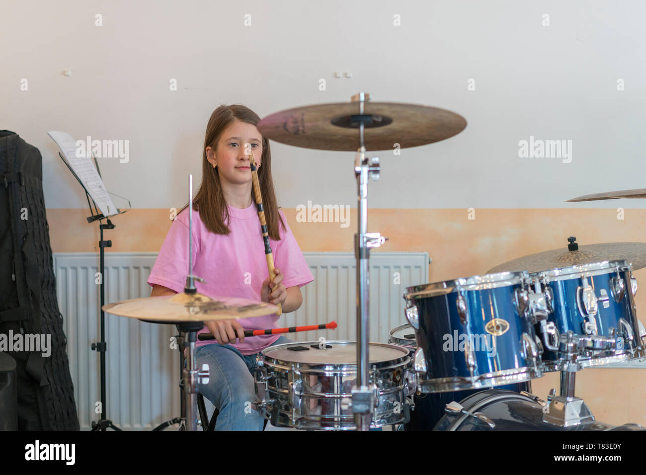 Little caucasian girl drummer playing the elettronic drum kit and