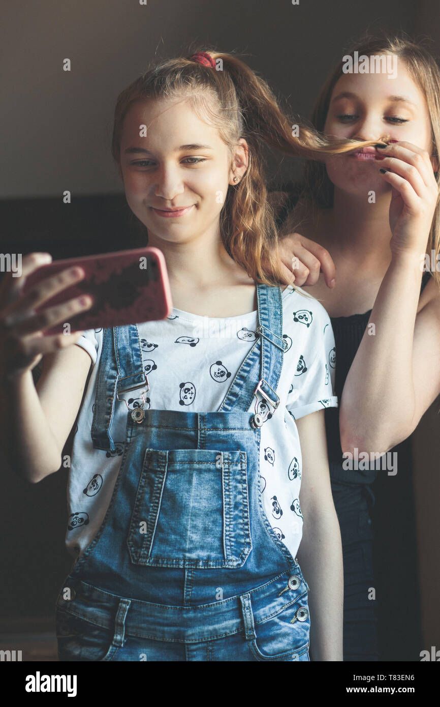 Young women taking selfie, using smartphone camera. Girls making faces ...