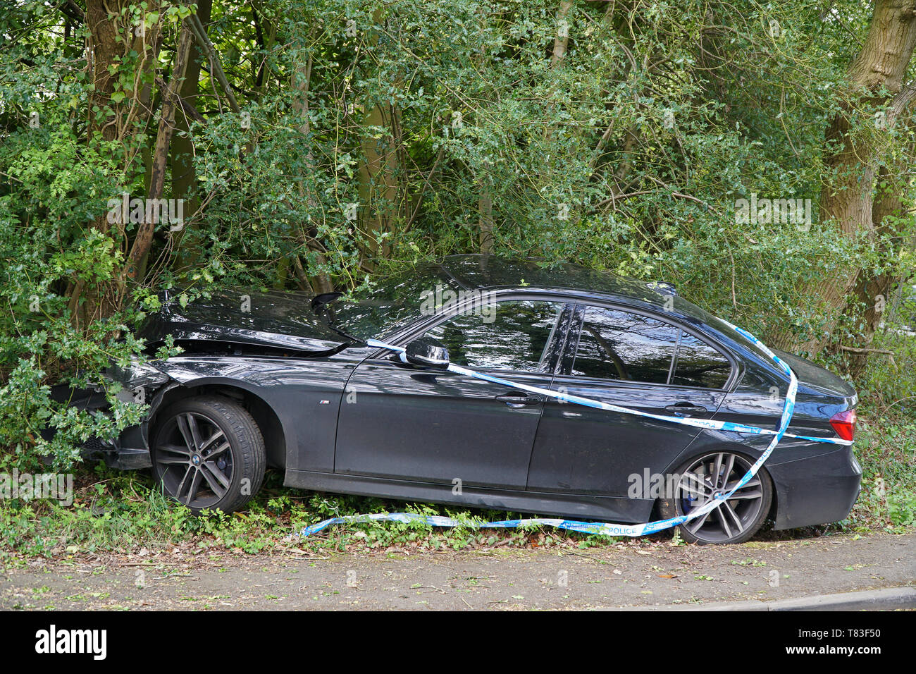 A single vehicle collision involving a car that has left the road at speed and mounted the pavement Stock Photo