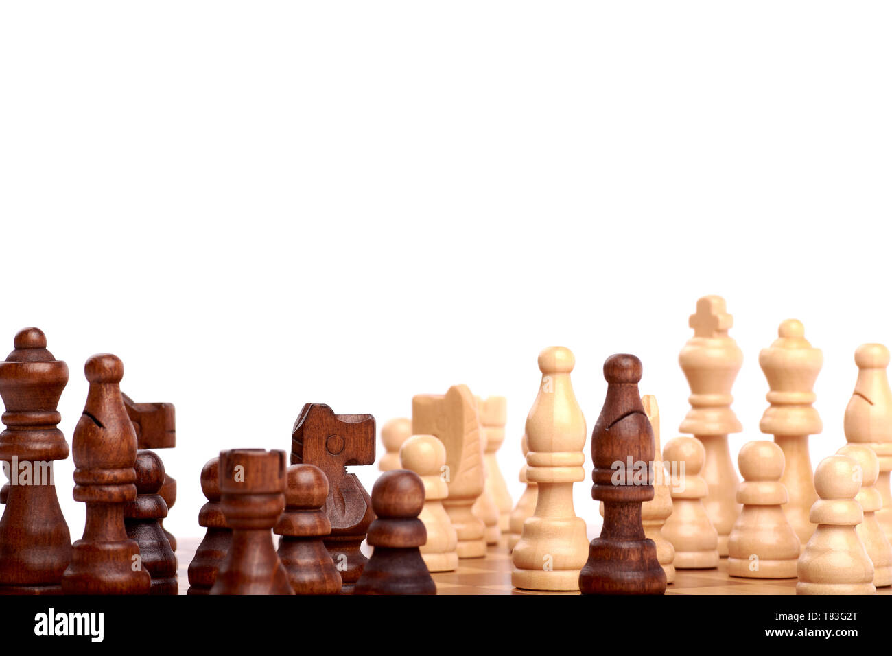 Close-up view of white and black chess pieces on a wooden chessboard in a scattered game. Isolated on white background Stock Photo