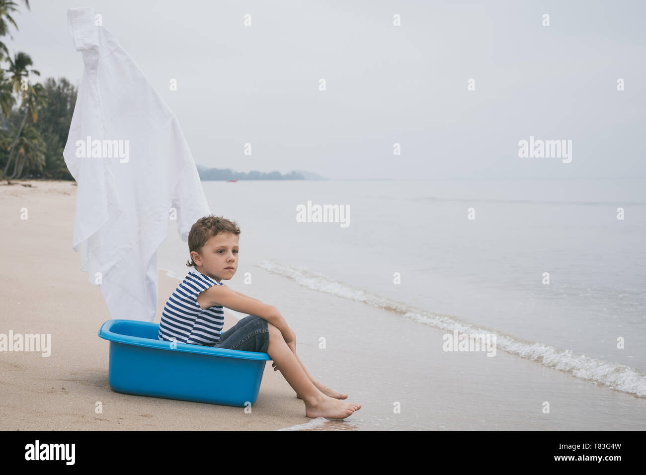One happy little boy playing on the beach at the day time.  Kid having fun outdoors. Concept of summer vacation. Stock Photo