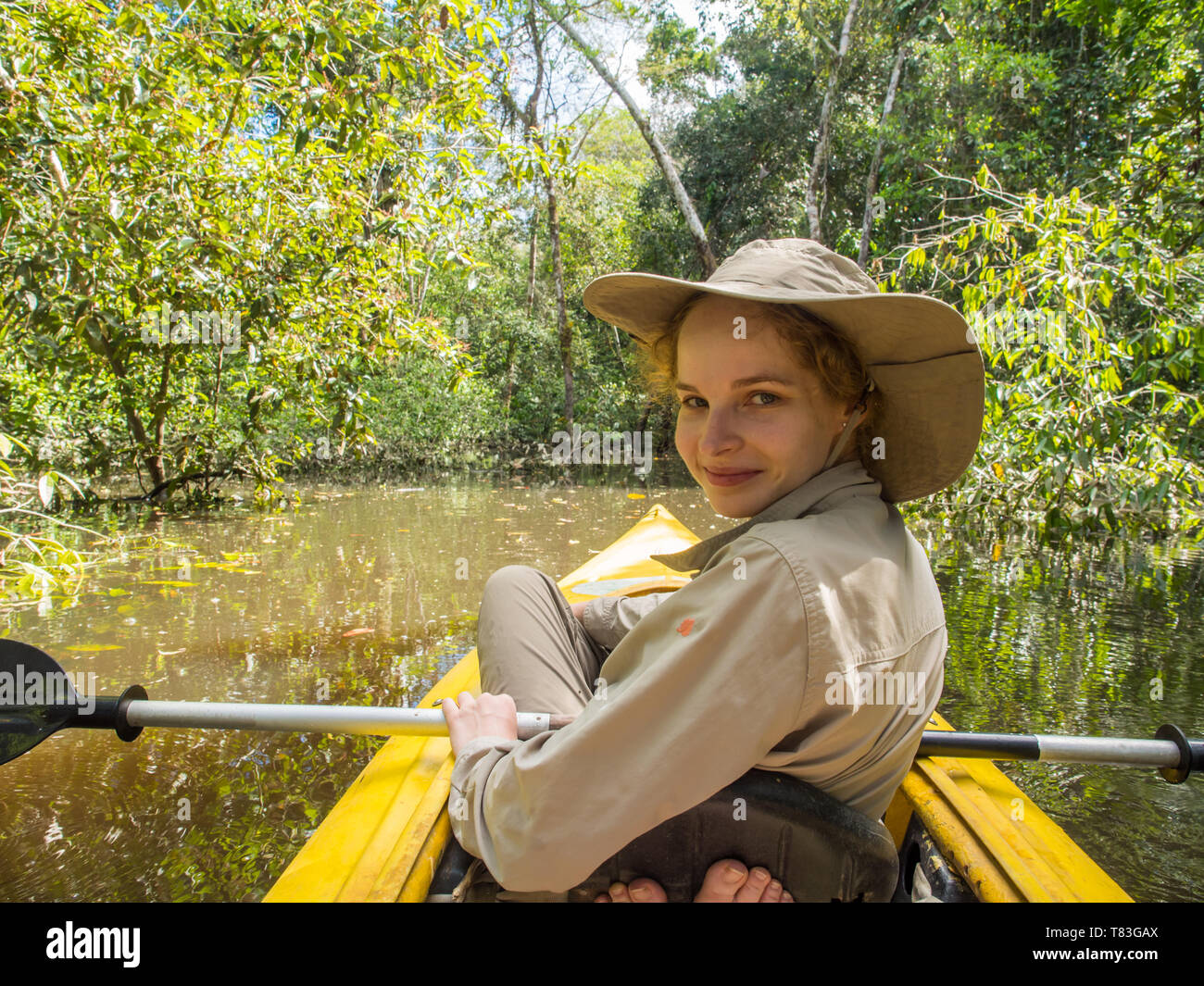 Jangle, Brazil - May 7, 2016: Young women  kayaking between the tree tops in the flooded jungle. Amazonia. Stock Photo