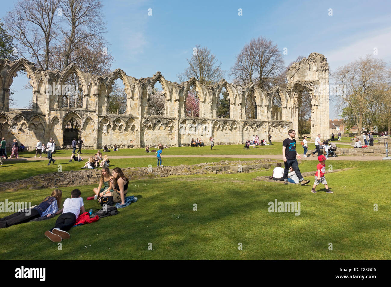 People visitors enjoying the spring weather near ruins of St Marys Abbey Museum Gardens York North Yorkshire England UK United Kingdom Great Britain Stock Photo
