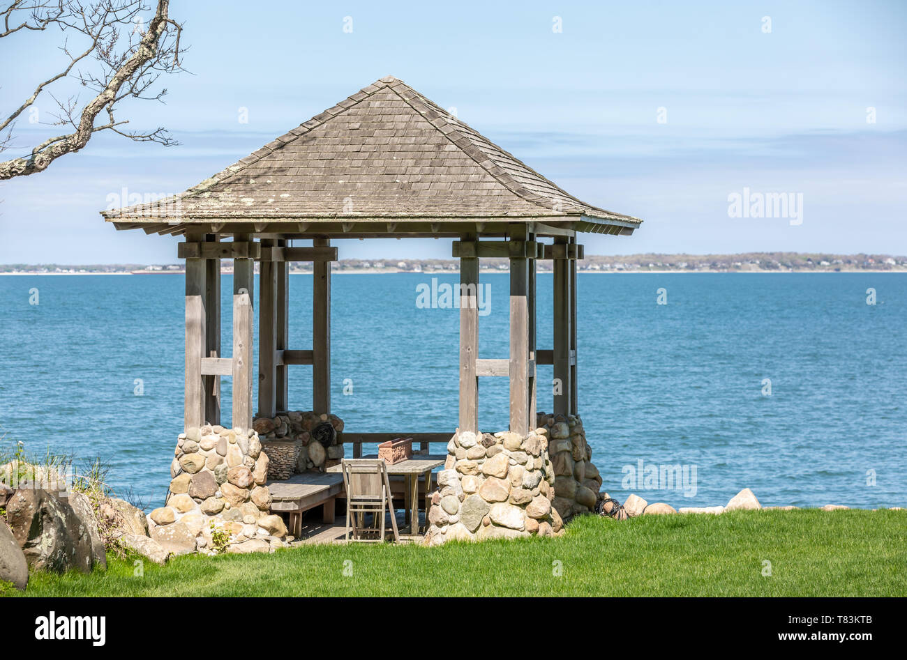 small wood and stone gazebo with bay beyond Stock Photo
