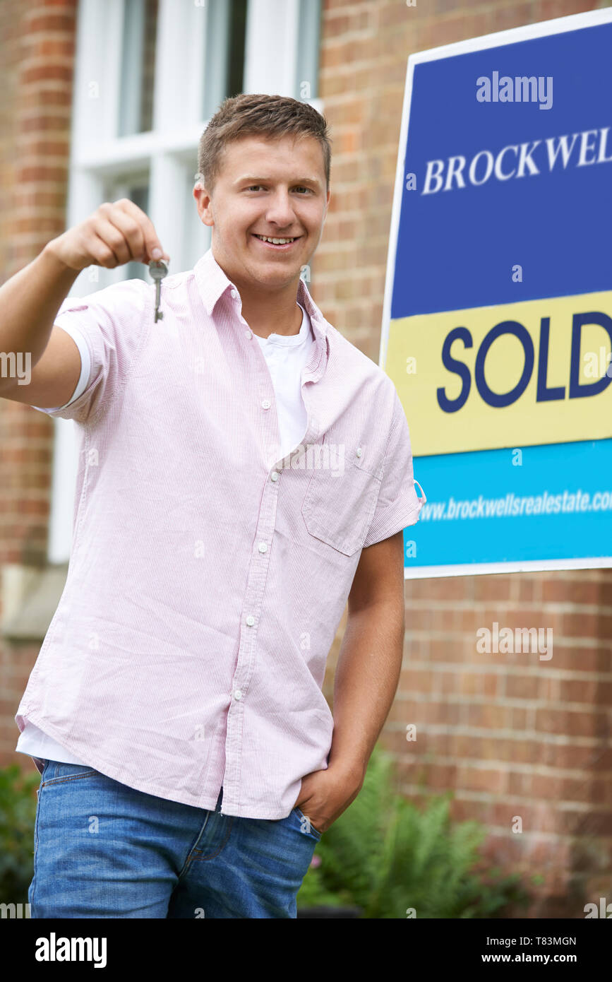 Portrait Of Excited Man Standing Outside New Home With Sold Sign ...