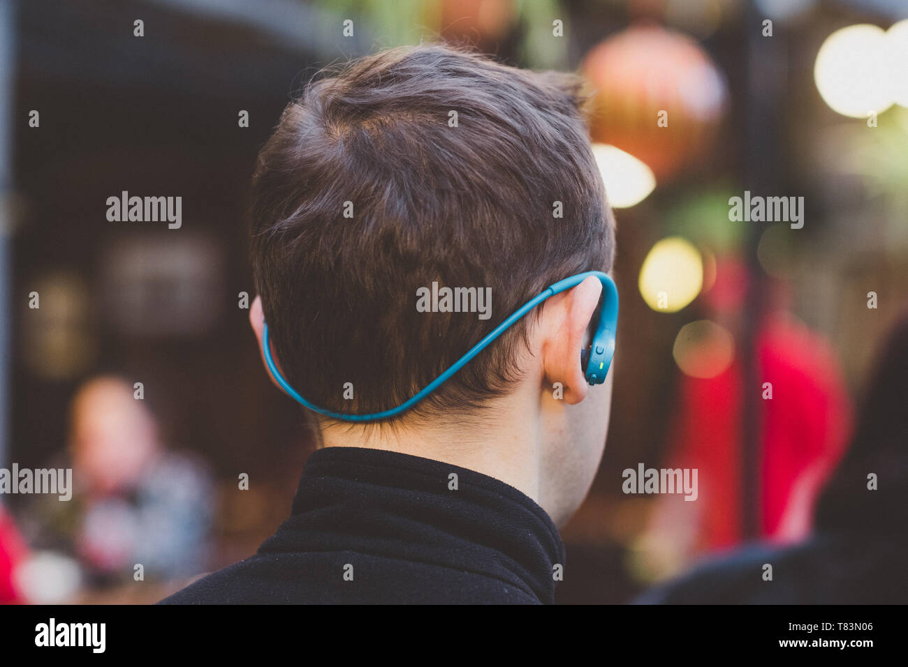 Back view of a young man with headphones posing in the city streets Stock Photo