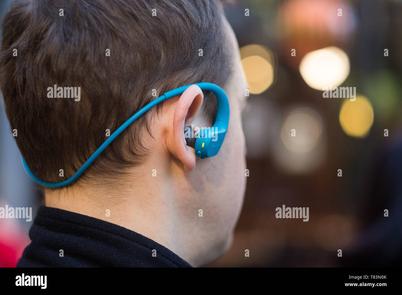 Back view of a young man with headphones posing in the city streets Stock Photo
