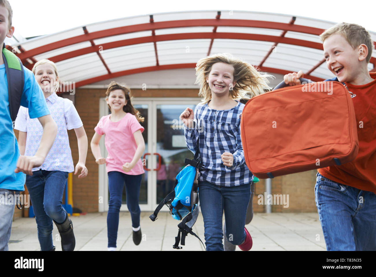 Group Of Elementary School Pupils Outside Classroom At End Of Lessons Running Across Playground Stock Photo