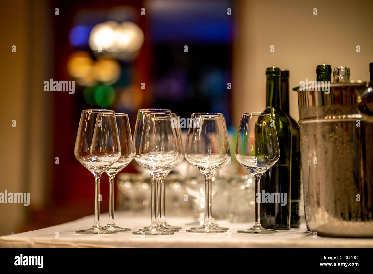 Empty glasses, wine bottles and bucket with ice on table in restaurant. Ice bucket, wine glasses and bottles arranged on the table for wedding recepti Stock Photo