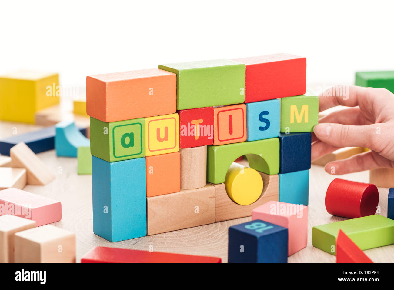 Hand Using Building Blocks partial view of female hand near autism lettering made of colorful ...