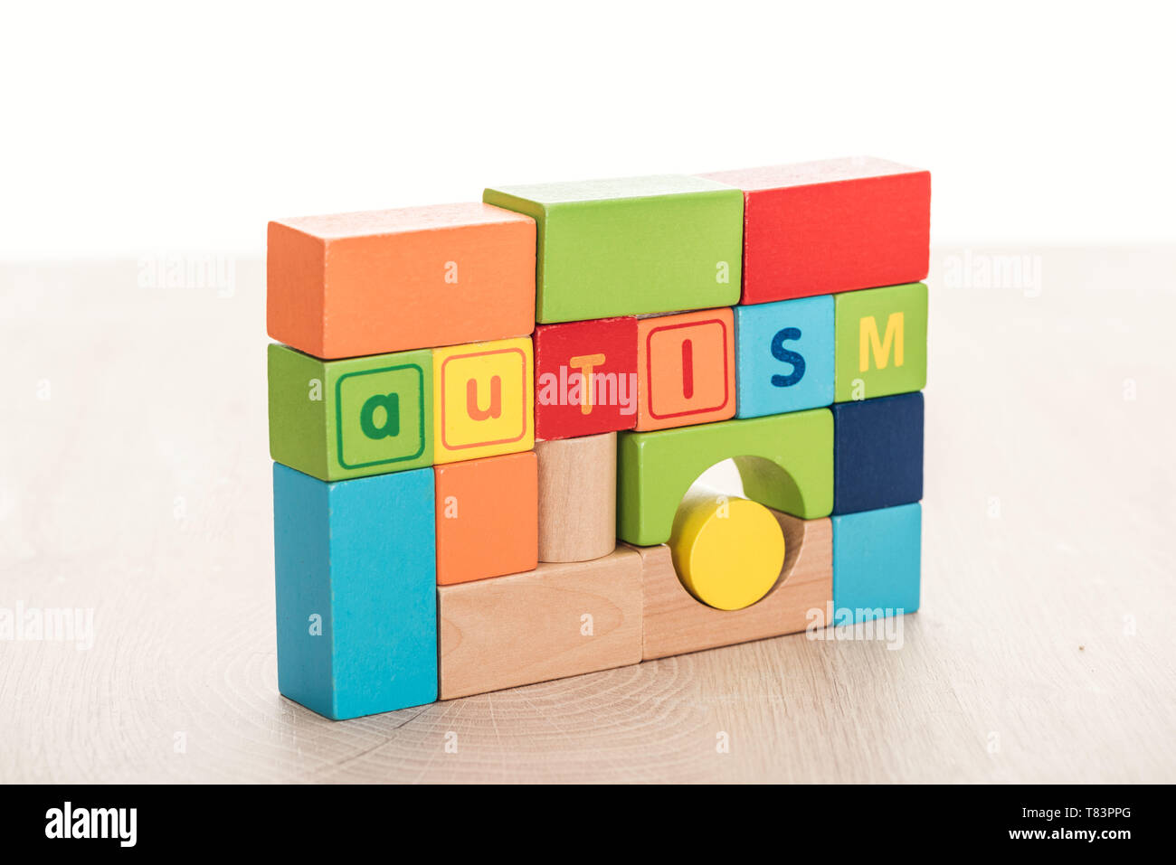 autism lettering made of multicolored building blocks on wooden surface ...