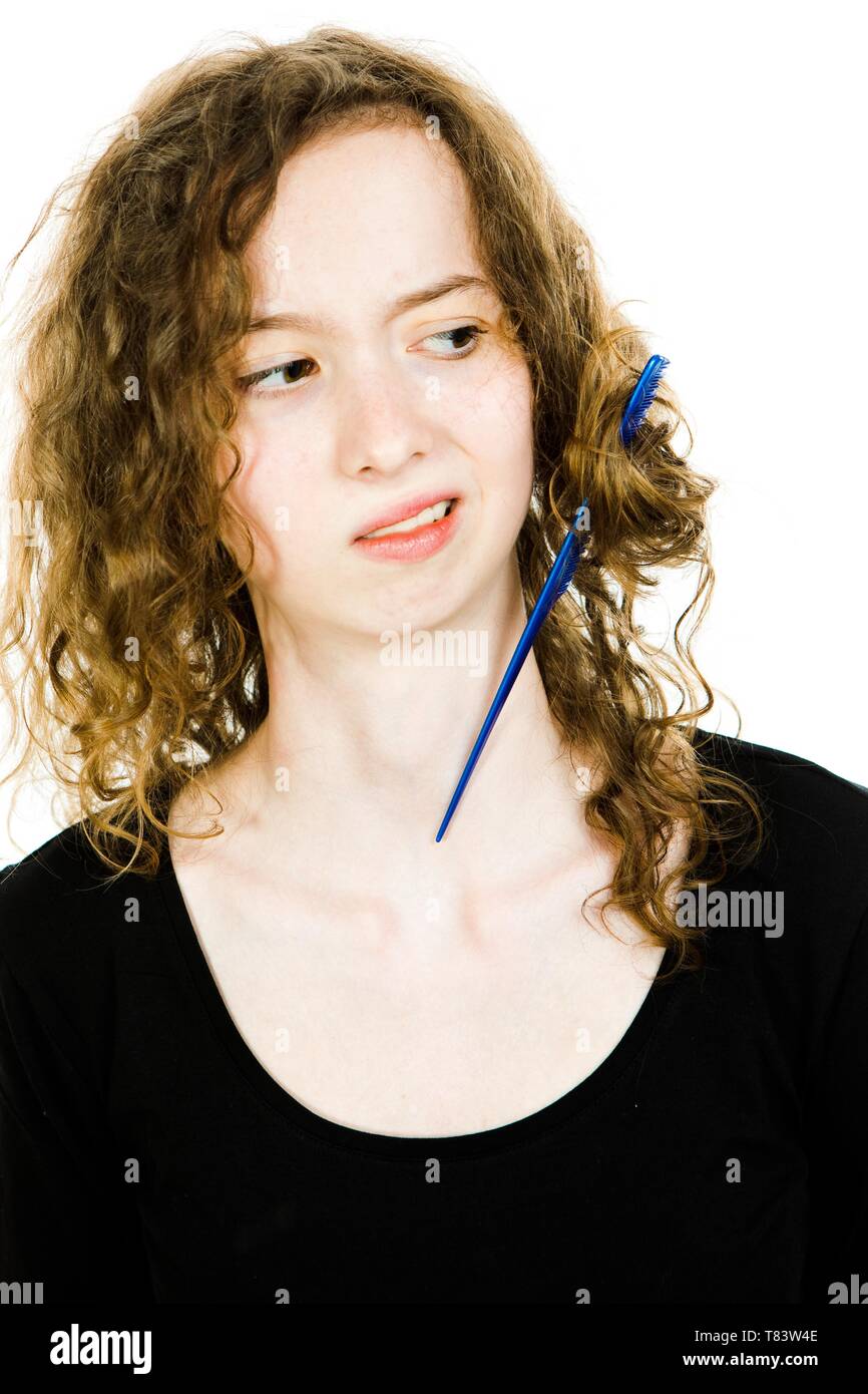 Teenaged blond girl with hair having tangled hair dressing problem