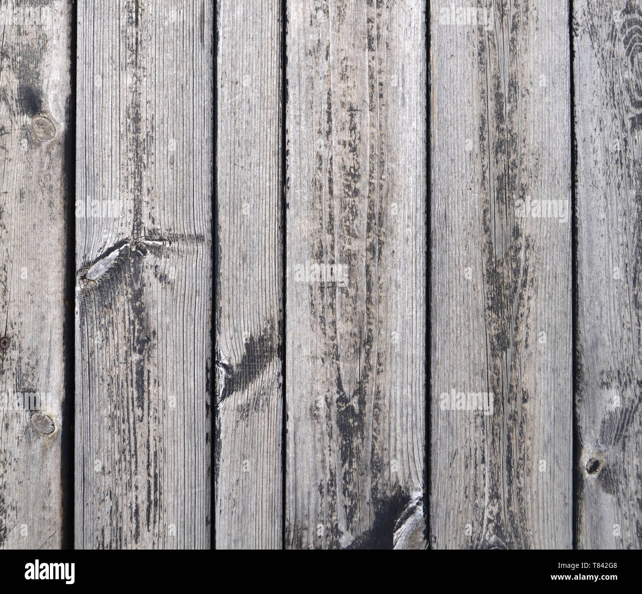 Close-up view to vertically oriented grey planks of old wooden garden table under the sunshine. Stock Photo