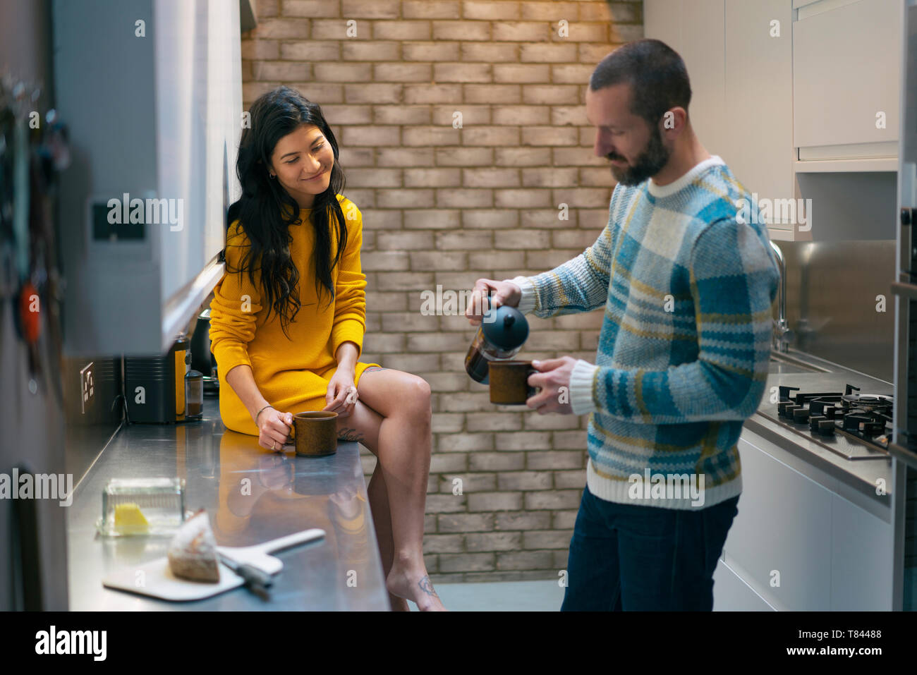 Hipster couple having coffee and talking in kitchen Stock Photo