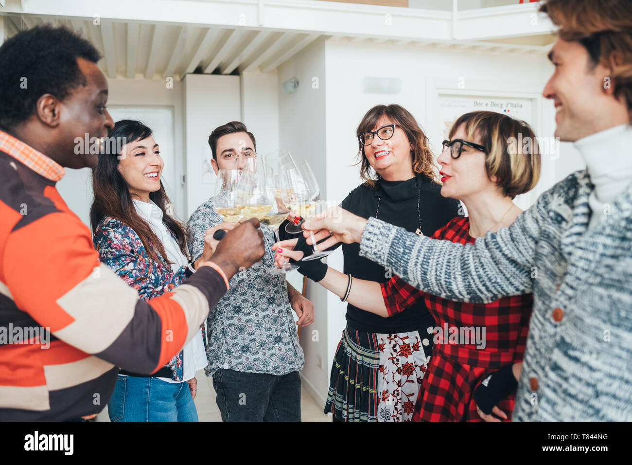 Friends toasting white wine in loft office Stock Photo