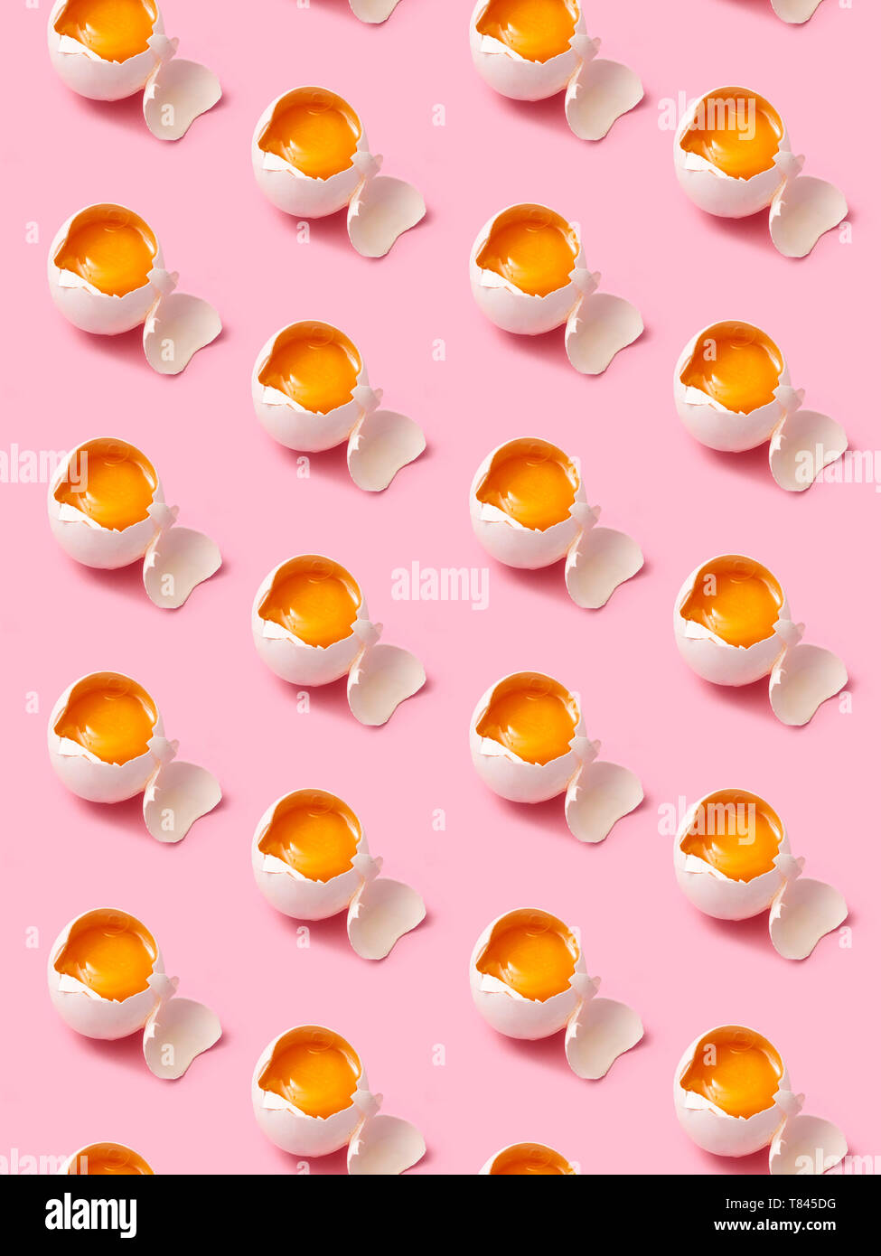 Broken eggs arranged in rows on pink background Stock Photo