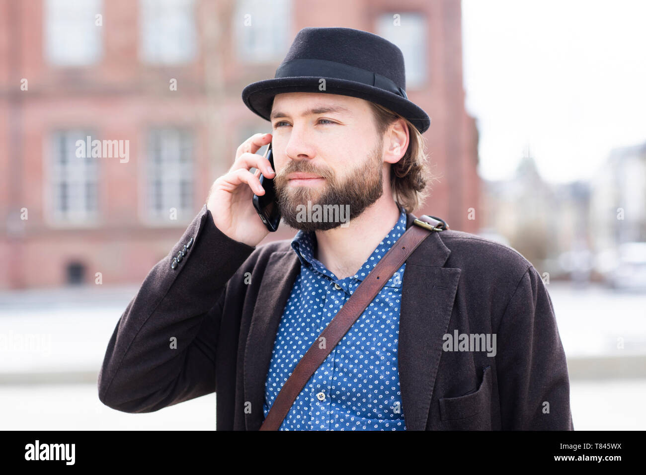 Man in trilby making smartphone call on city street Stock Photo