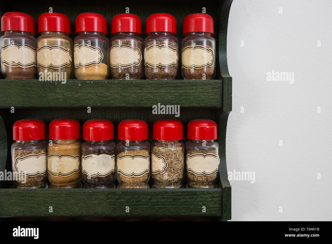 Jars of herbs and spices in wooden rack on white background, vintage