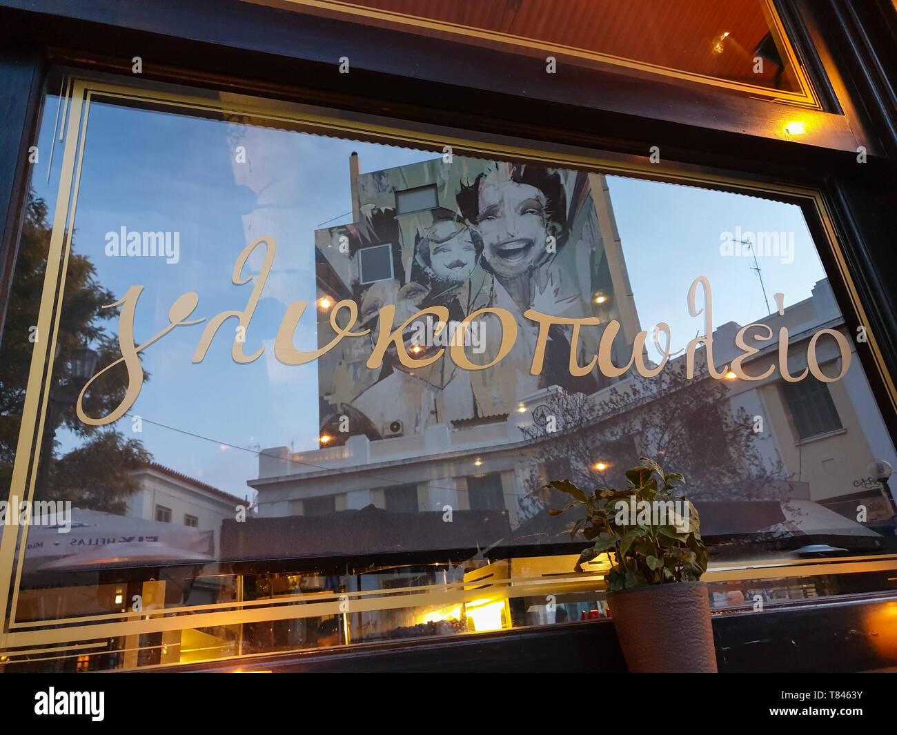 Athens, Greece - March 9, 2019: Reflection in a pastry shop window of graffiti on a building facade in Heroes' square in Psirri neighborhood of centra Stock Photo