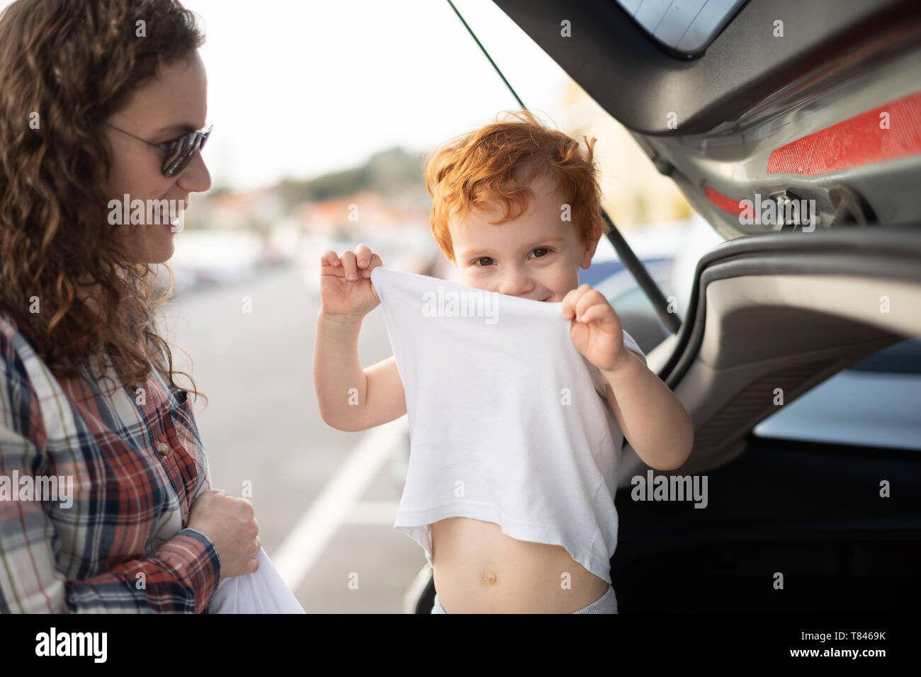 Boy getting fresh change of clothes at car boot Stock Photo