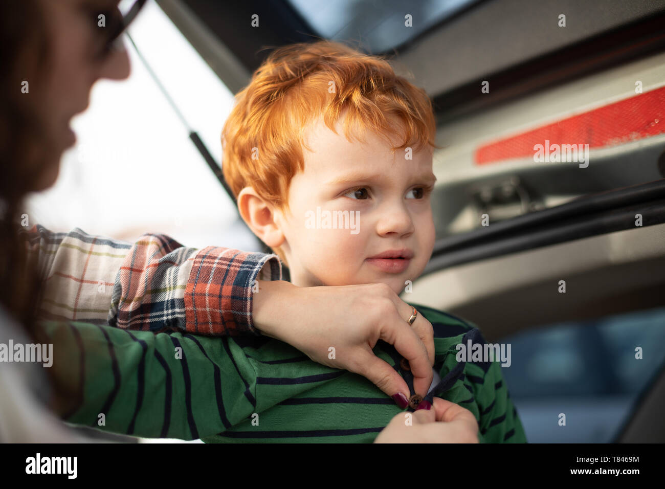 Boy getting fresh change of clothes at car boot Stock Photo