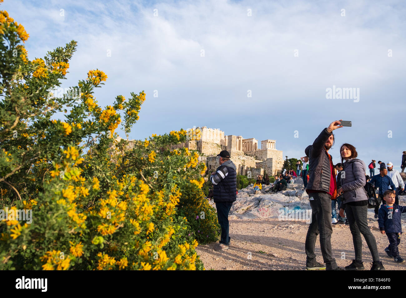 Athens, Greece - March 9, 2019: Tourists take selfies on Areopagus Hill against the Acropolis of Athens in the background Stock Photo