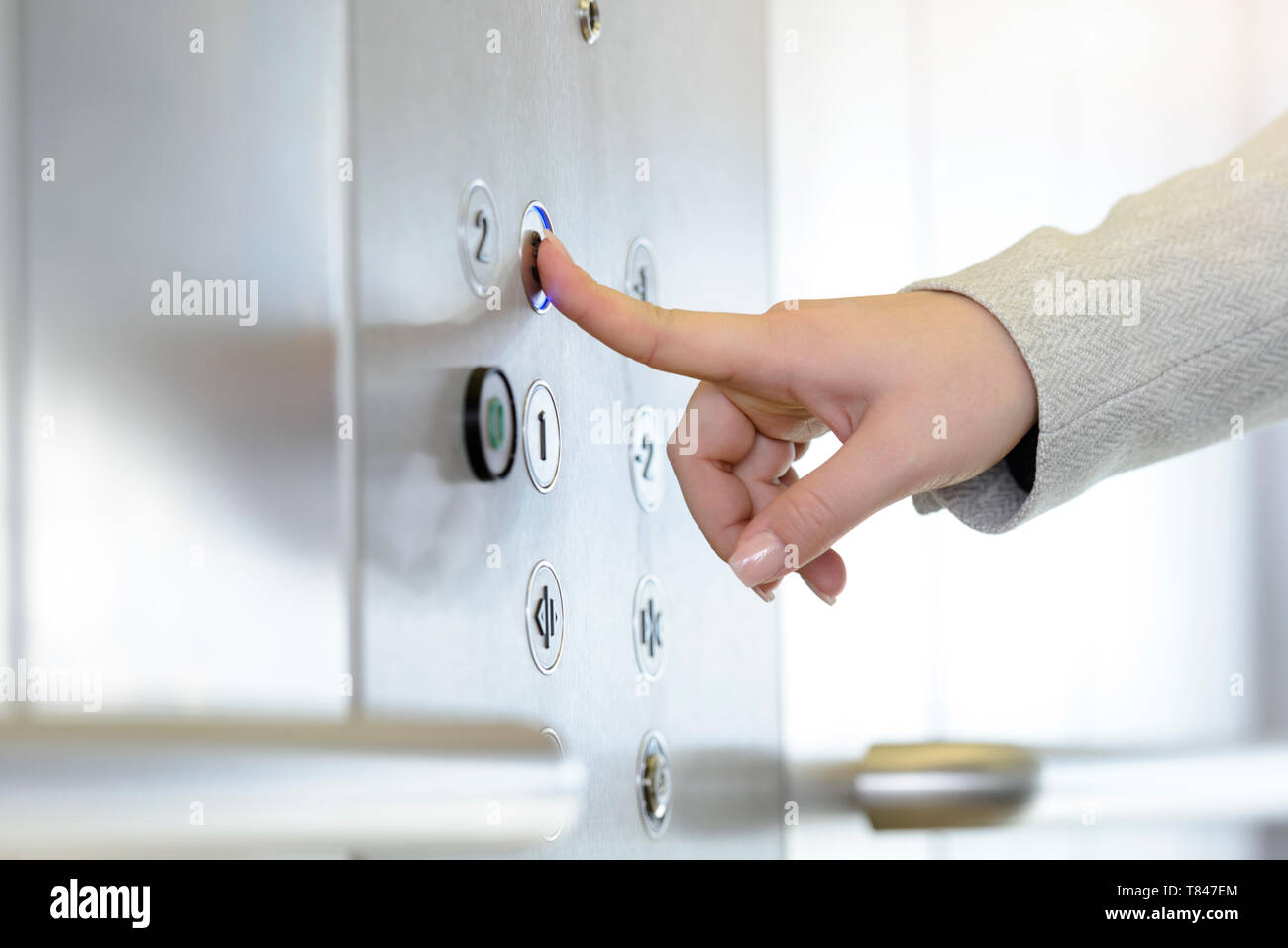 Woman pressing button inside elevator Stock Photo
