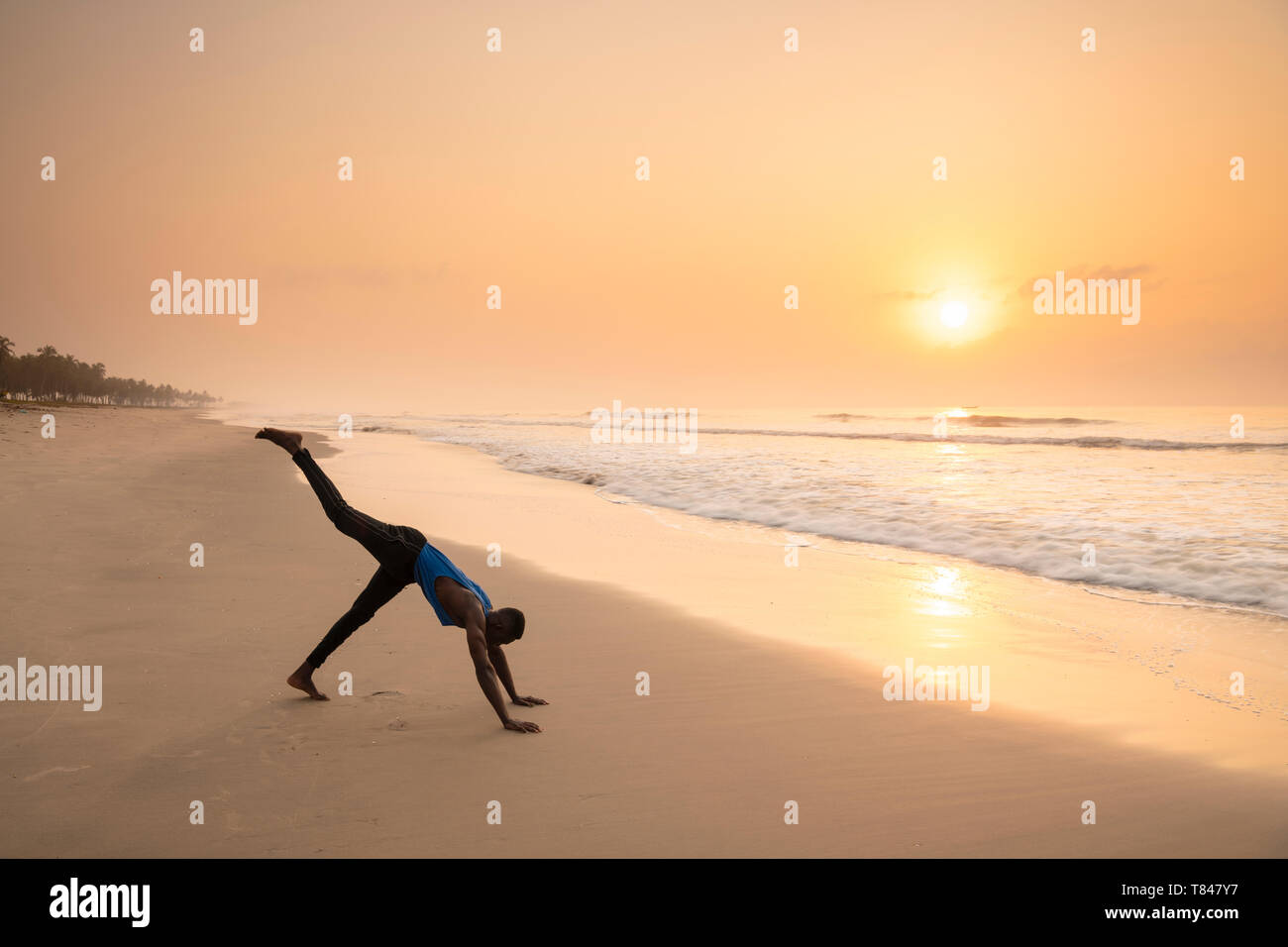 Man practising yoga on beach Stock Photo
