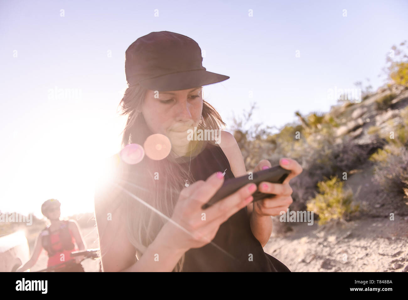 Woman operating drone (unmanned aerial vehicle) using smartphone on rural dirt track Stock Photo
