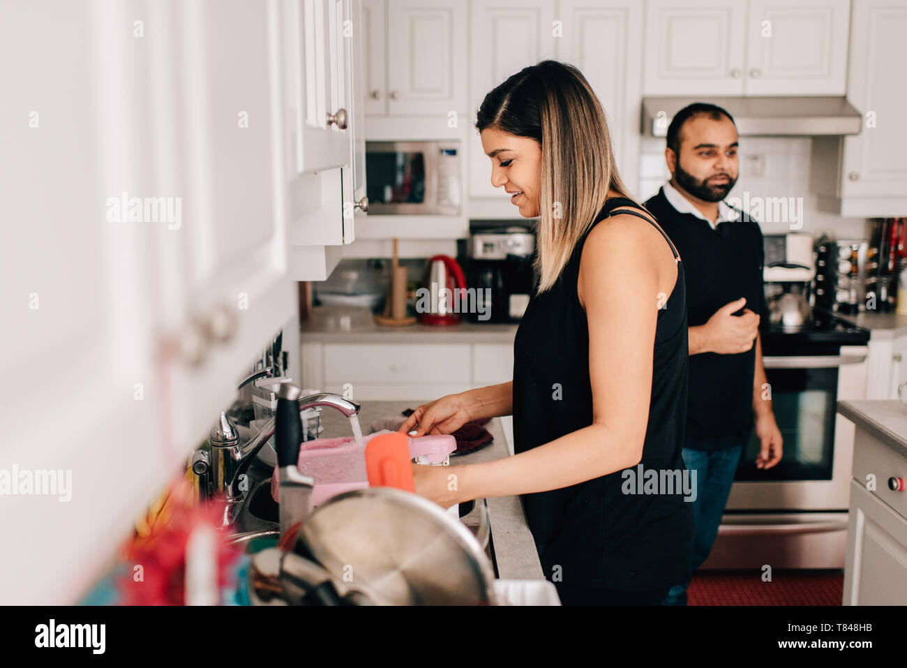 Mid adult couple in kitchen washing dishes Stock Photo