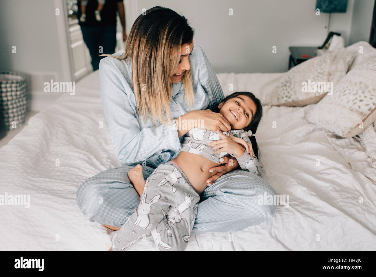 Girl being tickled by her mother on bed in morning Stock Photo - Alamy