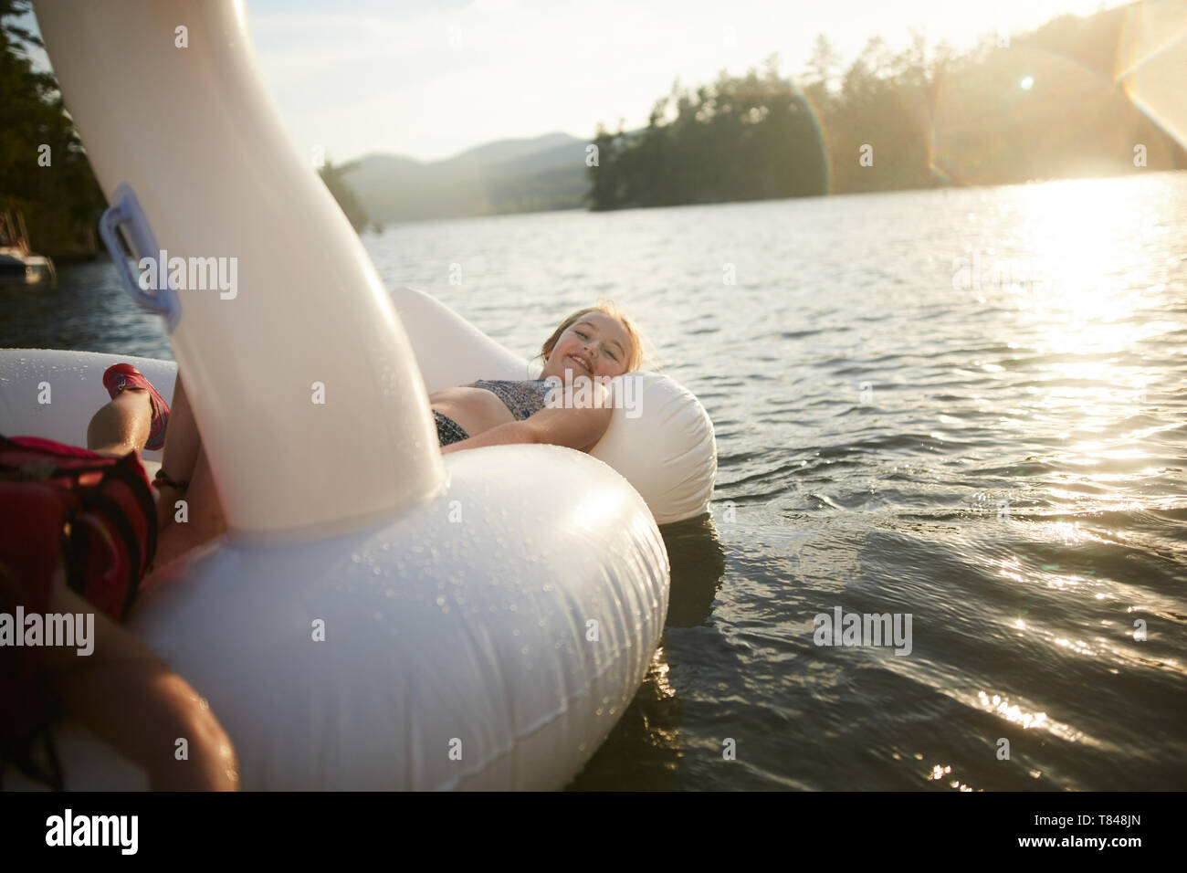 Girls playing on inflatable swan in lake Stock Photo