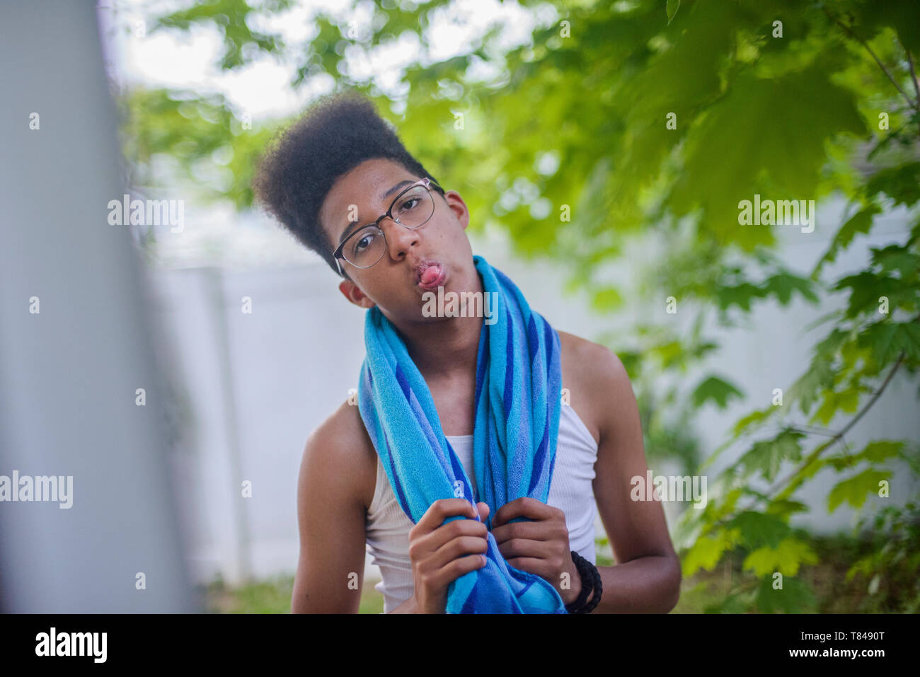 Teenage boy with afro flat top hairstyle sticking out tongue in garden, portrait Stock Photo