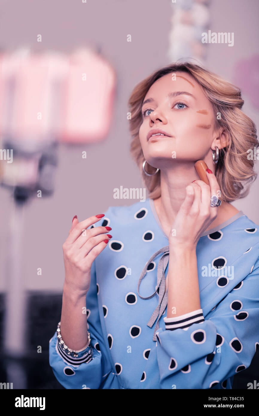 Woman With Short Wavy Hair Putting Some Concealer On Her Neck