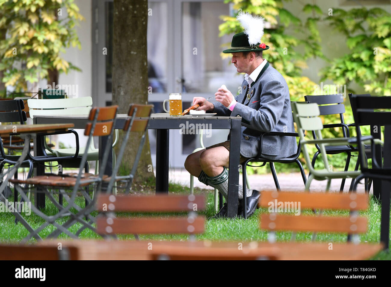 A Trachtler, man in Bavarian costume, sitting in a beer garden with beer and Weisswurst. on the grounds of Herrmannsdorfer Landwerkstaetten-an organic farm in Glonn (southeast of Munich). Visit of the Prince of Wales and the Duchess of Cornwall in Bavaria on 10.05.2019. | usage worldwide Stock Photo