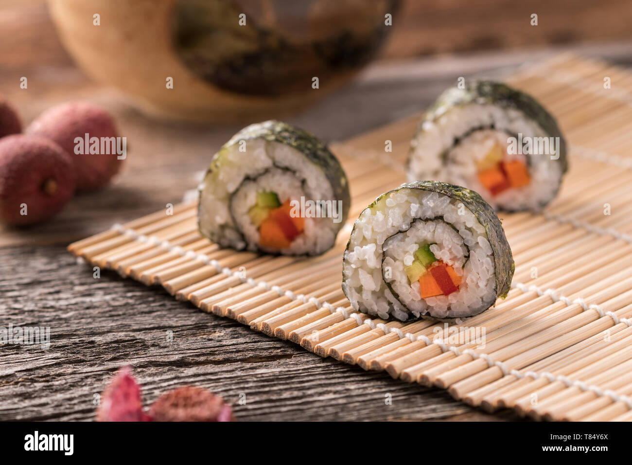 Three Maki Sushi Rolls On Bamboo Mat On Wooden Surface