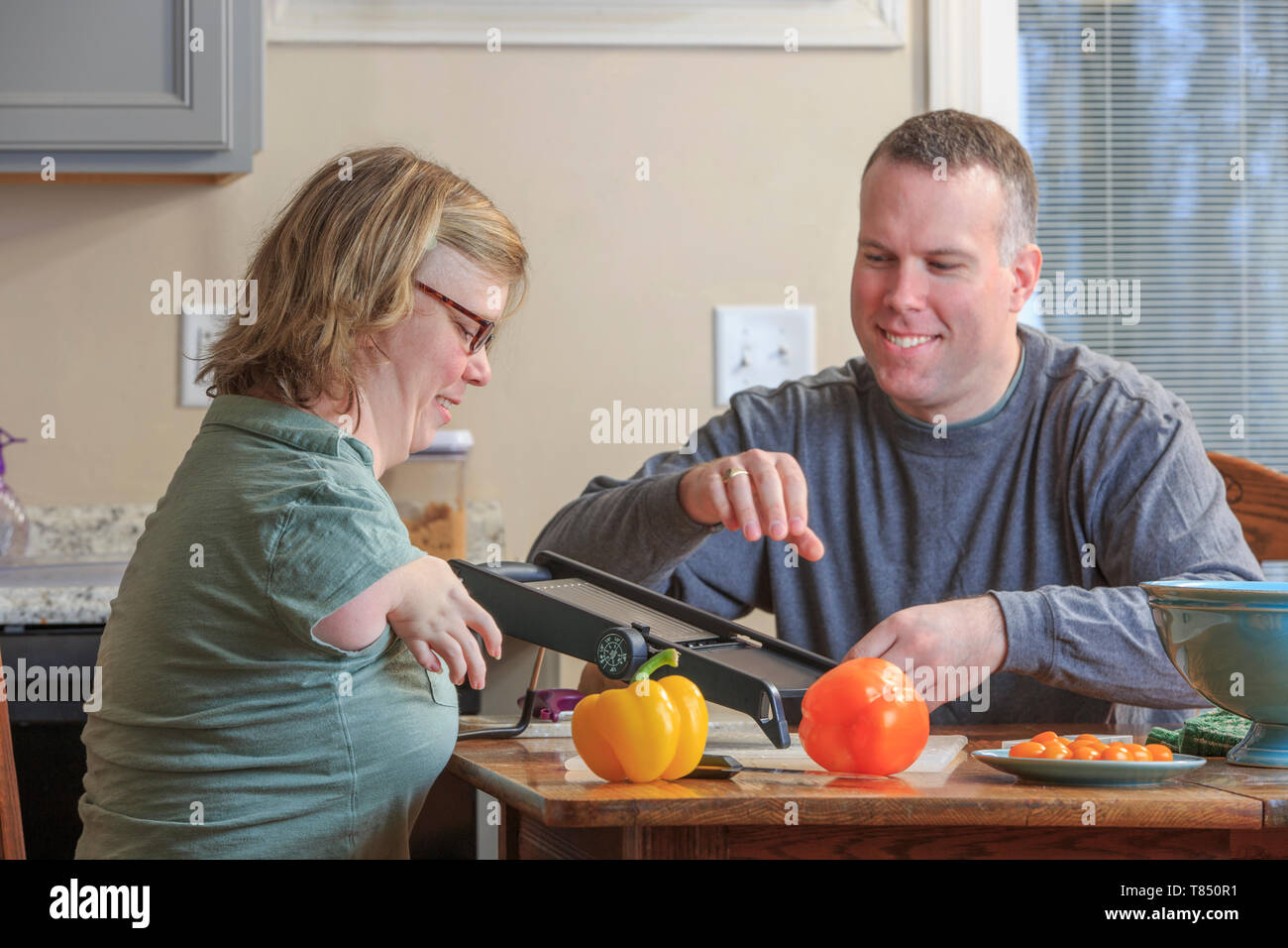 Woman with TAR Syndrome and her husband grating vegetables in the kitchen Stock Photo