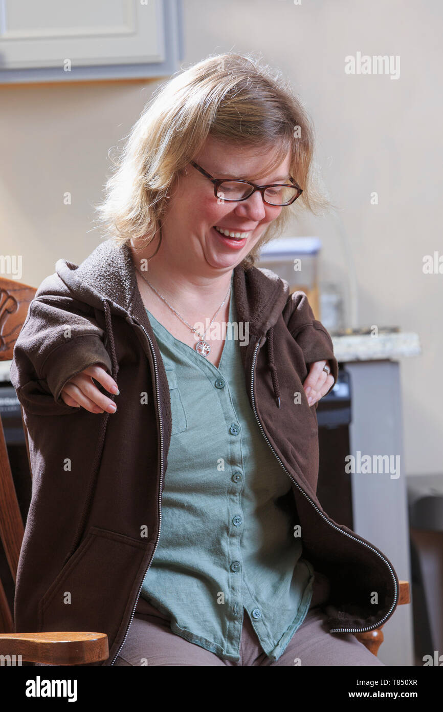 Woman with TAR Syndrome putting on her jacket Stock Photo