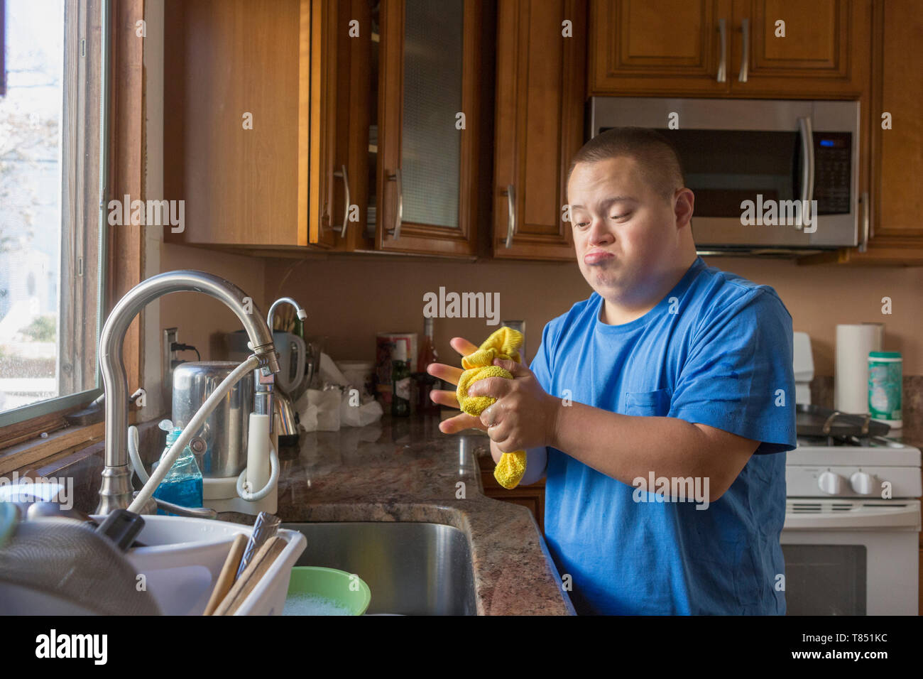 Teen with Down Syndrome doing dishes Stock Photo