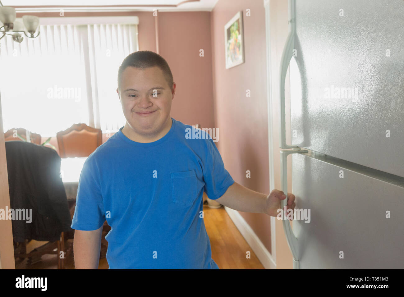 Teen boy with Down Syndrome opening refrigerator Stock Photo