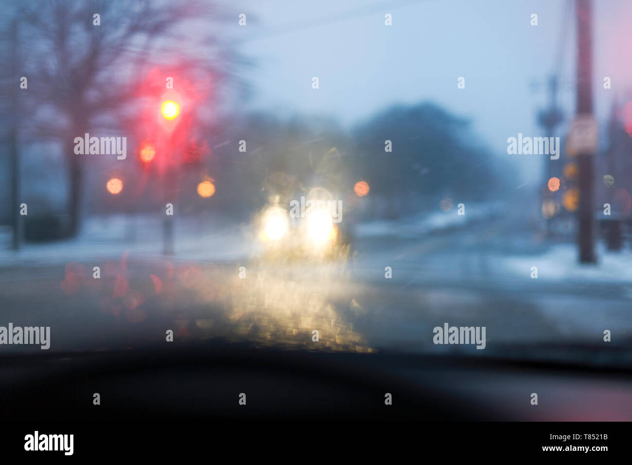 A road in bad weather view through a car windscreen, traffic lights on