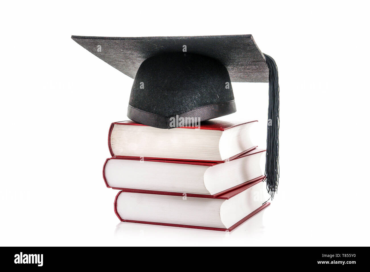 Black graduation hat on pile of three hard cover books over white Stock Photo