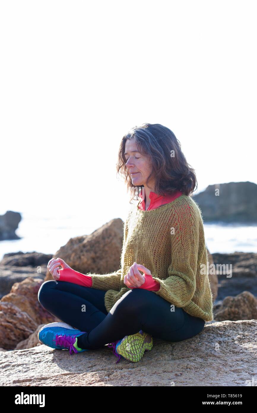 Woman meditating next to the sea Stock Photo