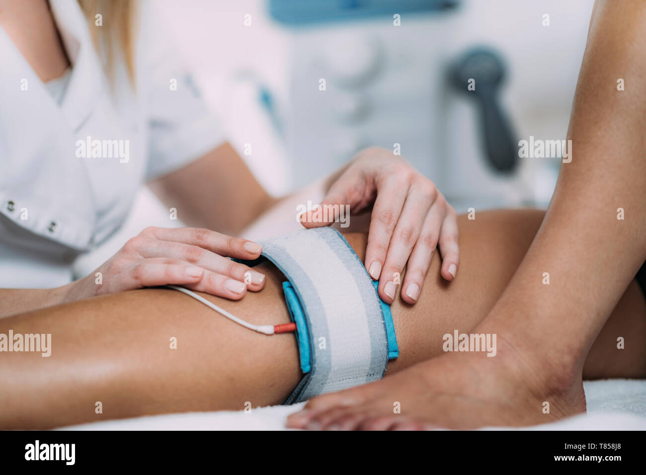 Electrical muscle stimulation in physical therapy. Therapist positioning  electrodes on a patient's knee Stock Photo - Alamy